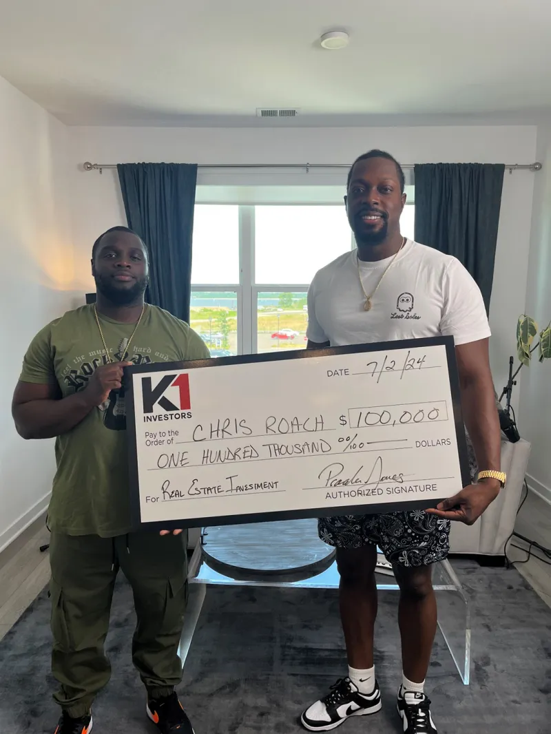 Chris Roach holding a $100,000 K1 Investors real estate investment check